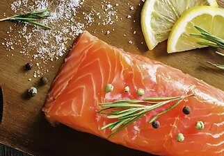 Fresh salmon fillet garnished with rosemary and lemon slices.