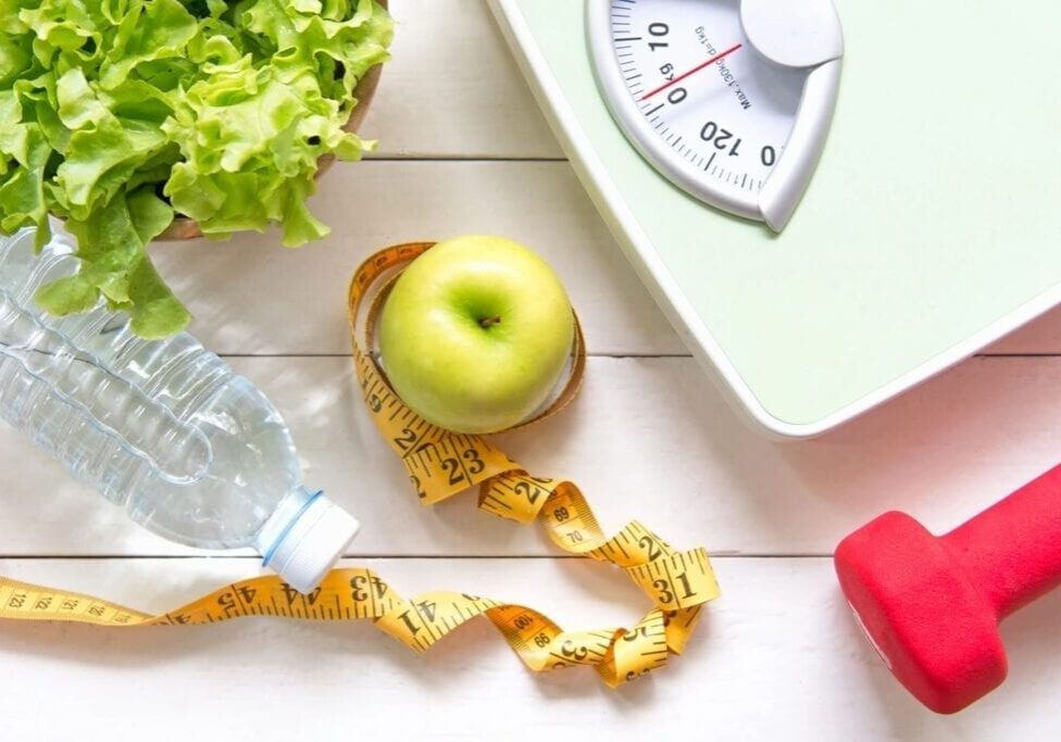 Healthy lifestyle essentials with apple, water, and scale.