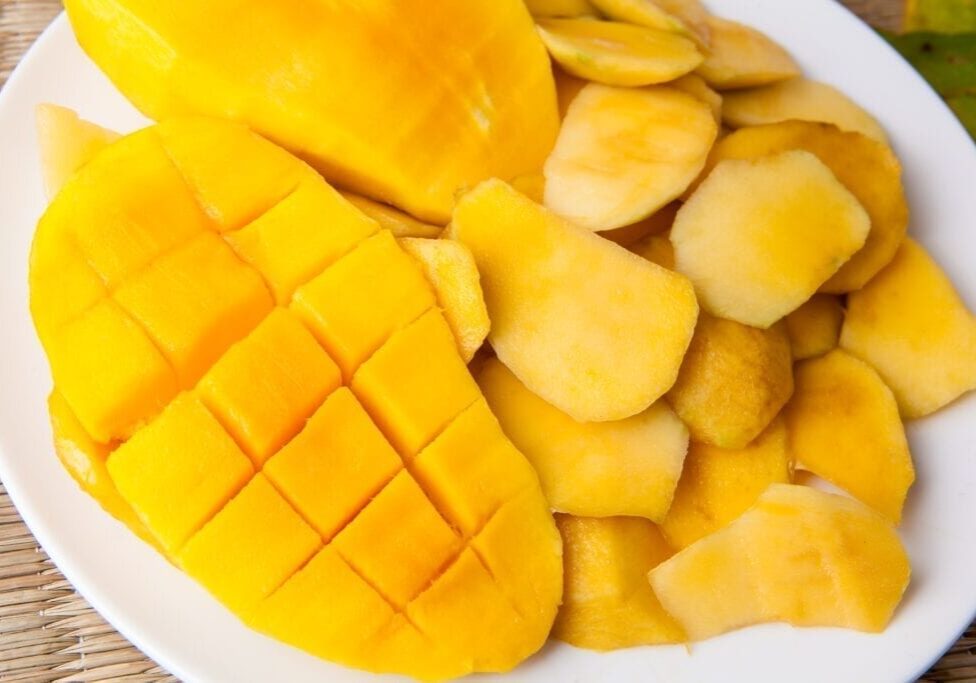 Fresh mango slices with diced and peeled pieces on a plate.